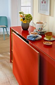 Orange sideboard with sliding doors and decorative utensils