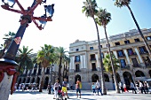 Tourists on Placa Reial with palm trees and street lantern, Barcelona, Spain