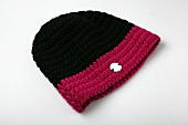 Close-up of black and red knitted woolen hat on white background