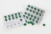 Green shiny pills packs with pills on background