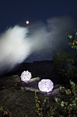 Illuminated glass lamps on stones with smoke