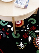 Close-up of round table on black carpet with colourful pattern