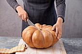Close-up of woman cutting pumpkin on wooden board