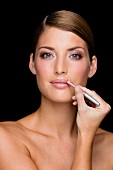 Portrait of pretty woman with gray eyes, applying lip liner with pencil