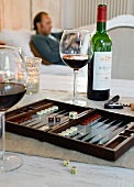 Close-up of backgammon board game with bottle of red wine and wine glasses