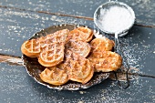 Millet waffles on plate and icing sugar in sieve
