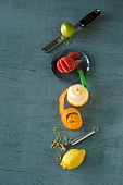 Various citrus fruits, peeler and knives on green background, overhead view