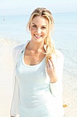 Blonde, sporty woman with long hair in a light shirt on the beach