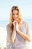 Blonde woman with long hair in a crochet shirt on the beach