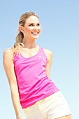 Blonde, sporty woman with long hair in a pink shirt on the beach