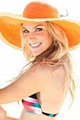 Blonde woman with long hair in a bikini and an orange straw hat