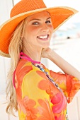 Blonde woman with long hair in a colorful blouse and orange straw hat