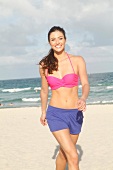 Sporty woman with long dark hair in a bikini on the beach