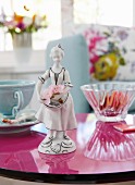 Blumenmädchen-Figur aus bemaltem Porzellan auf runder Tischplatte in spiegelndem Magenta