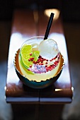 A Caipirinha with pink peppercorns and round ice cubes
