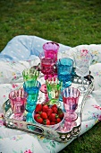 Silver platter with colorful glasses and strawberries
