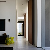Gangflucht in südamerikanischem Wohnhaus mit gelben Glasvasen auf poliertem Betonboden und raumhohen Paneelen aus exotischem Holz