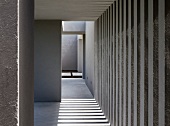Collage of grey stripes and light formed by wall elements and apertures outside a South American house