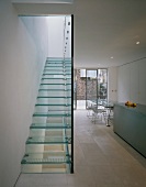 Treppenansicht der Glasstufen und Glastrennwand in offener Designerküche mit Essplatz