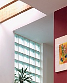 Raumhoher Durchgang neben rotgetönter Wand und Blick auf Glasbausteinfenster mit Zimmerpflanze