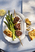 A beef kebabs with green asparagus and unleavened bread