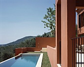 Sun above a pool in a garden and Mediterranean home with a reddish brown facade