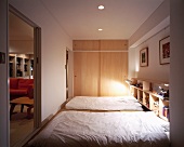 Mattresses on the floor in front of wardrobe with wooden sliding doors