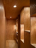 Narrow hallway with wood paneling on the wall and ceiling and built-in shelves made of wood