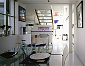 Gedecke auf Esstisch mit Glasplatte im offenen modernenen Wohnraum mit Treppe