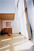 Minimalist living room with a light curtain in front of a tall window