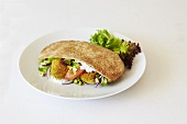 Falafel in a pitta bread against a white background