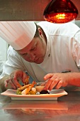 A head chef serving prawns on avocado tartar with a dip