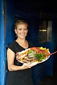 A young woman holding a platter of shellfish