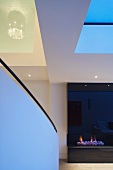 Ausschnitt vom Wohnraum mit Treppengeländer und Kaminfeuer mit schwarzer spiegelnder Verkleidung