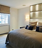 Double bed with ceiling-height upholstered head in modern bedroom