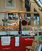 Vintage Küchenzeile mit rot lackierter Front und hängenden Pfannen und Töpfen