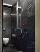 Designer bath with black marble tiles on the wall and floor and integrated vanity