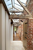 Renovierter Flur mit alter Ziegelfassade und rustikaler Holzkonstruktion unter Oberlicht