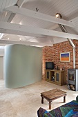 Renovated living room with brick wall and white lacquered wood ceiling, underneath a modern, horse shoe shaped installation