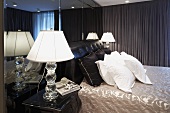 Men's bedroom with bedside table lamps beside white pillows on a double bed with dark green curtains