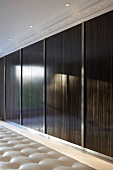 Holzschiebetüren mit glänzender Oberfläche und Deckenstrahler vor Stuckfries in eleganter Ankleide