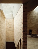 Modern house with brick walls and view through a passage to an armchair