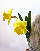 Blond lady holding two daffodils