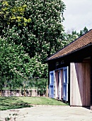 Bauernhaus mit blau lackierten Türladen und sonniger Garten