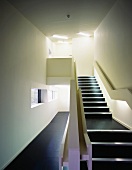 Minimalistisches Treppenhaus mit schwarzem Bodenbelag im Flur und auf Treppenstufen