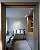 View through a door into a work room with counter and recessed ceiling spotlights above a built-in cabinet