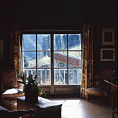 Dunkler Wohnraum mit Barocksesseln neben Balkontüren und Bergblick