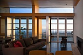 Moderner Wohnraum mit braunem Sofa vor Kamin und Terrassenfenster
