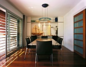 Black leather chair with chrome legs in a dining room in front of terrace doors with wooden blinds