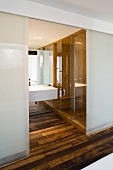 Open sliding door made of opaque glass providing a view of the wash stand in a designer bathroom